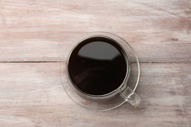 Bardakta sıcak kahve, ahşap masa, üst manzara.