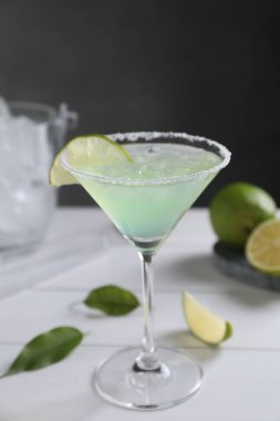 Lezzetli Margarita kokteyli beyaz ahşap masada limon ve cam.