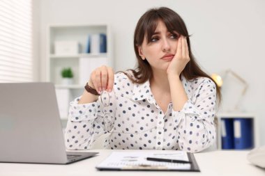 Overwhelmed woman sitting at table with laptop in office