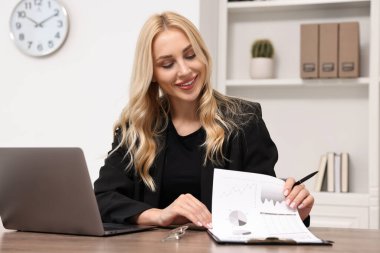 Happy secretary working with document at table in office
