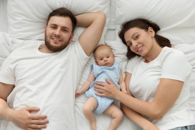 Mutlu bir aile. Anne babalar yataklarında sevimli bebekleriyle, üst manzaralı.