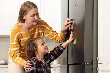 Anne ve kızı evdeki buzdolabına manyetik harfler koyuyorlar. Alfabe öğreniliyor