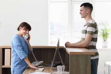 Smiling medical assistant working with patient at hospital reception