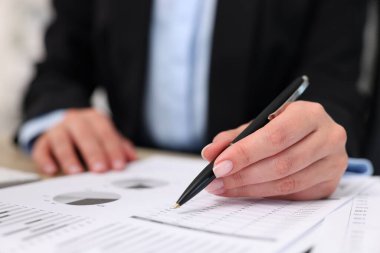 Secretary doing paperwork at table in office, closeup