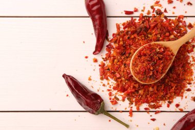 Beyaz ahşap masa üzerinde kırmızı biber taneleri ve kapsüller düz yatıyordu. Metin için boşluk