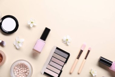 Farklı makyaj ürünleri ve bej arka planda güzel bahar çiçekleri ile düz kompozisyon, metin için boşluk