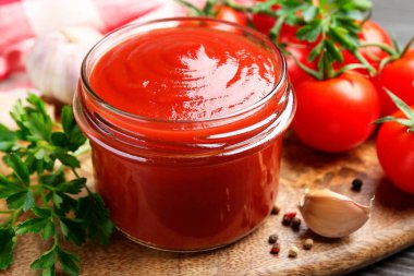 Lezzetli ketçap, taze domates, maydanoz ve baharatlar gri ahşap masada.