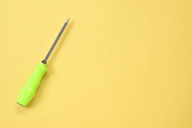 Açık sarı arka planda yeşil saplı tornavida, üst manzara. Metin için boşluk