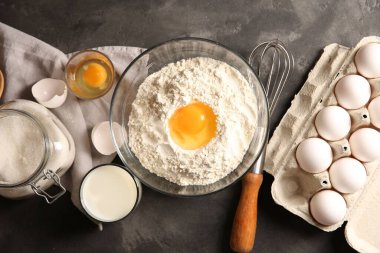 Para kazanmak. Kasede yumurta sarısı ve gri desenli masa üzerindeki diğer ürünlerle un, düz konum