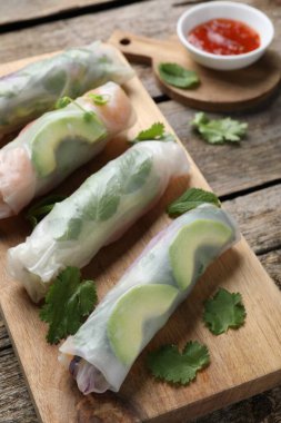 Delicious spring rolls and sauce on wooden table
