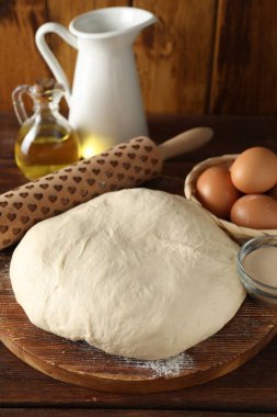 Çiğ hamur, merdane ve malzemeler ahşap masada.