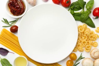 Beyaz arka planda farklı türde makarna ve ürünlerle çevrili bir tabak. Metin için boşluk