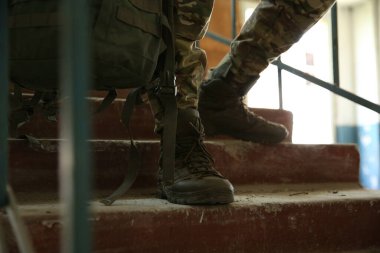 Military mission. Soldier in uniform on stairs inside abandoned building, closeup clipart
