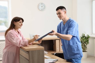 Smiling medical assistant working with patient at hospital reception
