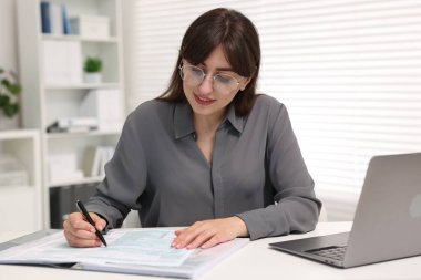 Smiling secretary doing paperwork at table in office