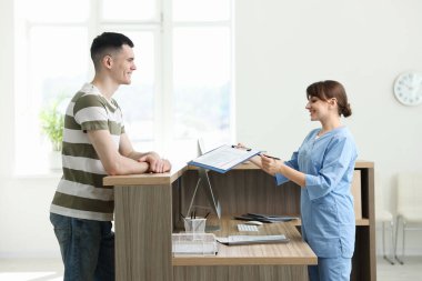 Smiling medical assistant working with patient at hospital reception
