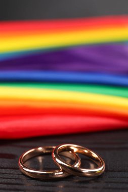 Gökkuşağı LGBT bayrağı ve siyah ahşap arka planda alyanslar, yakın plan