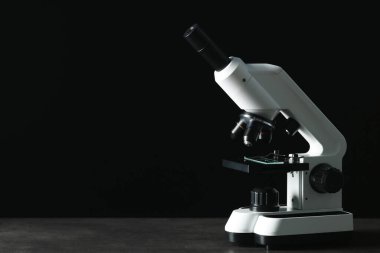 Siyah arkaplana karşı gri tabloda modern mikroskop, metin için boşluk