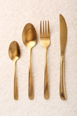 Hafif desenli masa üzerine serilmiş şık altın çatal bıçak seti.