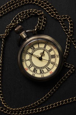 Siyah ahşap masa üzerinde zincirli cep saati, üst manzara.