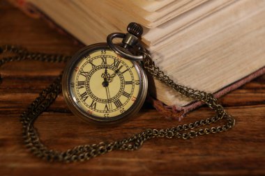 Zincirli cep saati ve kitap ahşap masada, yakın plan.