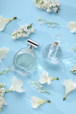 Lüks parfümler ve açık mavi arka planda çiçek dekoru.