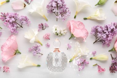 Parfüm ve çiçek dekoru beyaz arka planda, düz yerde.