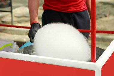 Man making cotton candy with machine outdoors, closeup