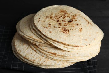 Pek çok lezzetli ev yapımı tortilla siyah ahşap masada, yakın plan.