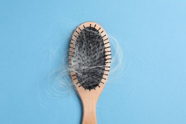 Açık mavi arka planda saçı dökülmüş ahşap fırça, üst manzara