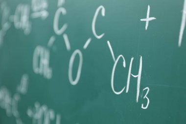 Yeşil tahtaya tebeşirle yazılmış kimyasal formüller, yakın plan.