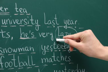 English teacher writing with chalk on green chalkboard, closeup clipart