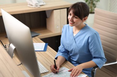 Smiling medical assistant working with documents in office