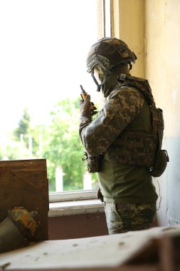 Military mission. Soldier in uniform with radio transmitter inside abandoned building clipart