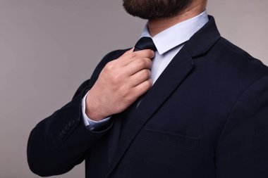 Gri arka planda takım elbiseli ve kravatlı iş adamı, yakın plan.