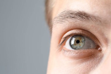 Mükemmel görüş. Gri arka planda güzel gözleri olan bir adam, yakın plan. Metin için boşluk