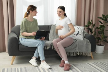 Doula evdeki kanepede hamile bir kadınla çalışıyor. Çocuk doğumu hazırlığı