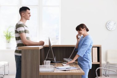 Smiling medical assistant working with patient at hospital reception