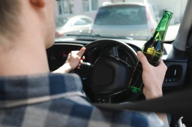 Bira şişesi sürücüsü arabası olan bir adam, yakın plan. İçkili araba kullanma.