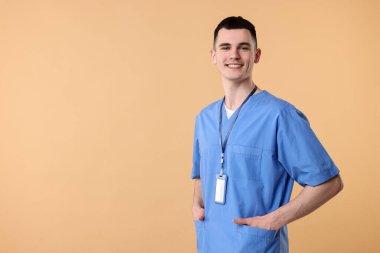 Portrait of smiling medical assistant on beige background. Space for text