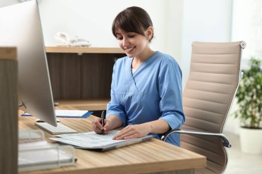 Smiling medical assistant working with documents in office