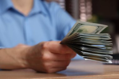 Para değişimi. Tahta masada elinde dolar banknotları tutan kadın, yakın plan.