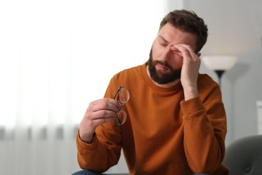 Overwhelmed man with glasses suffering at home. Space for text