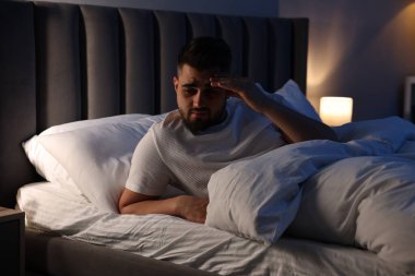 Yatakta uykusuzluk çeken sinirli bir adam.