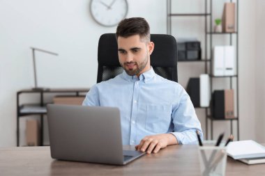 Ofiste dizüstü bilgisayarla çalışan mutlu genç programcı.