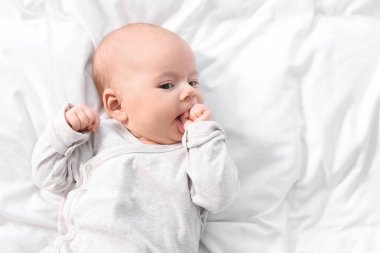 Beyaz çarşafların üzerinde uzanmış şirin bir bebek. Metin için boşluk