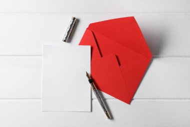 Beyaz ahşap masa üzerinde boş kağıt, kalem ve zarf, üst manzara. Metin için boşluk