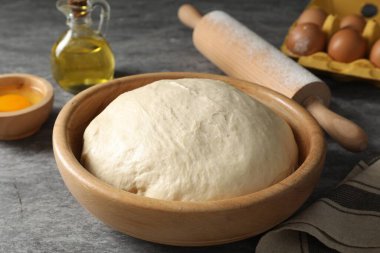 Çiğ hamur, merdane ve malzemeler gri masada.