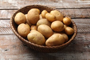 Tahta masada hasır sepette çiğ patates.