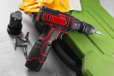 Elektrikli tornavida, çanta, matkap uçları, akü ve eldivenler ışık masasında, yakın plan.